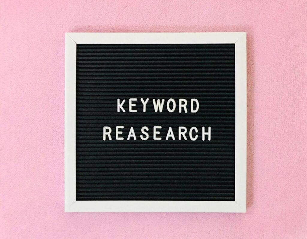 signe affichant “Keyword Research’’ sur un fond rose-recherche par mot-clé